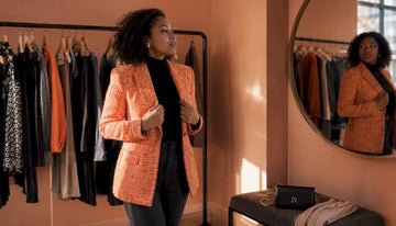 Woman trying on orange tweed blazer in boutique